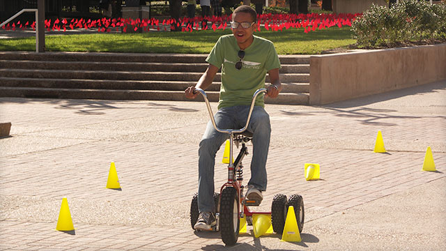 A person navigates a course on a tricycle. 