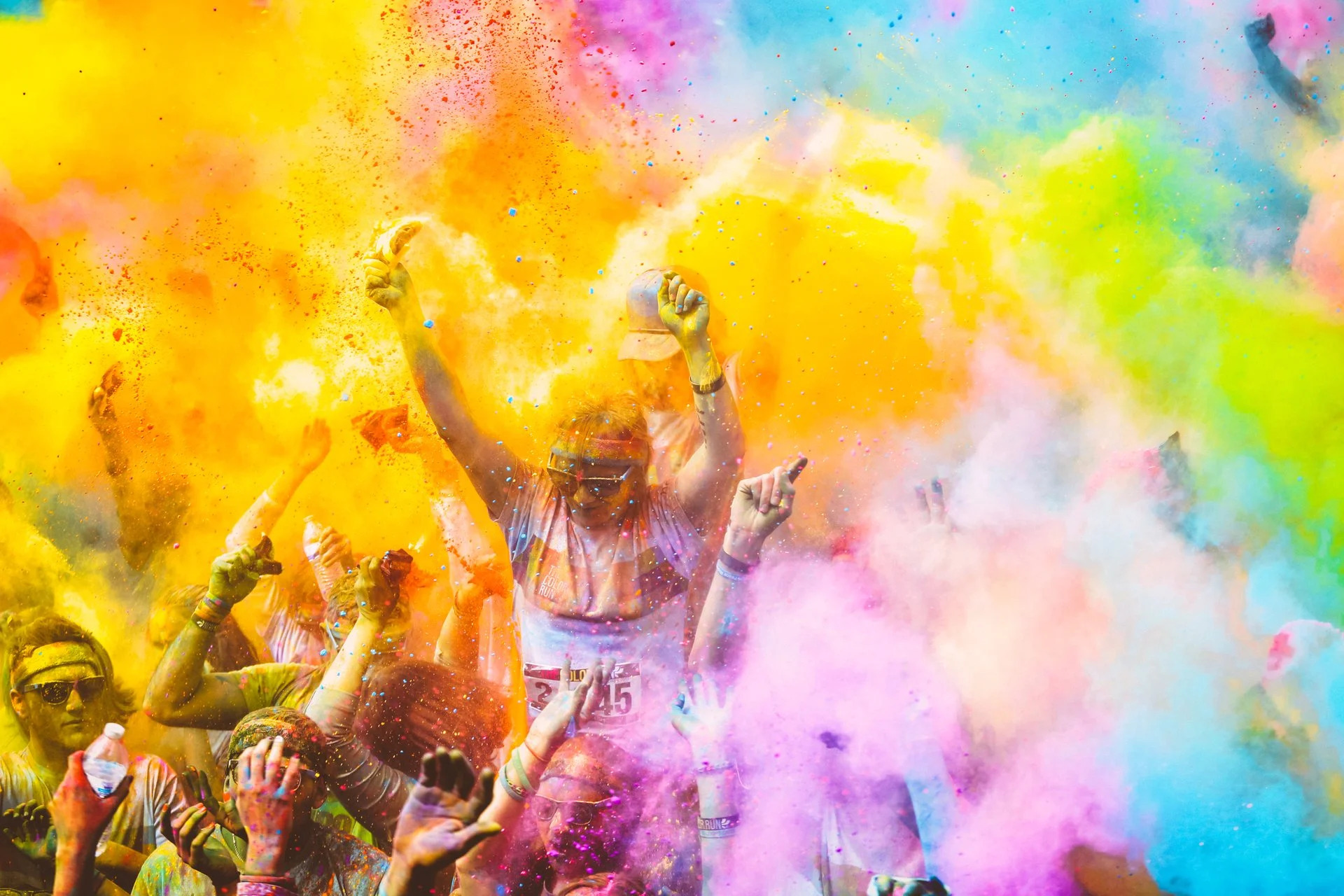 People with their arms raised, covered with colored powder.