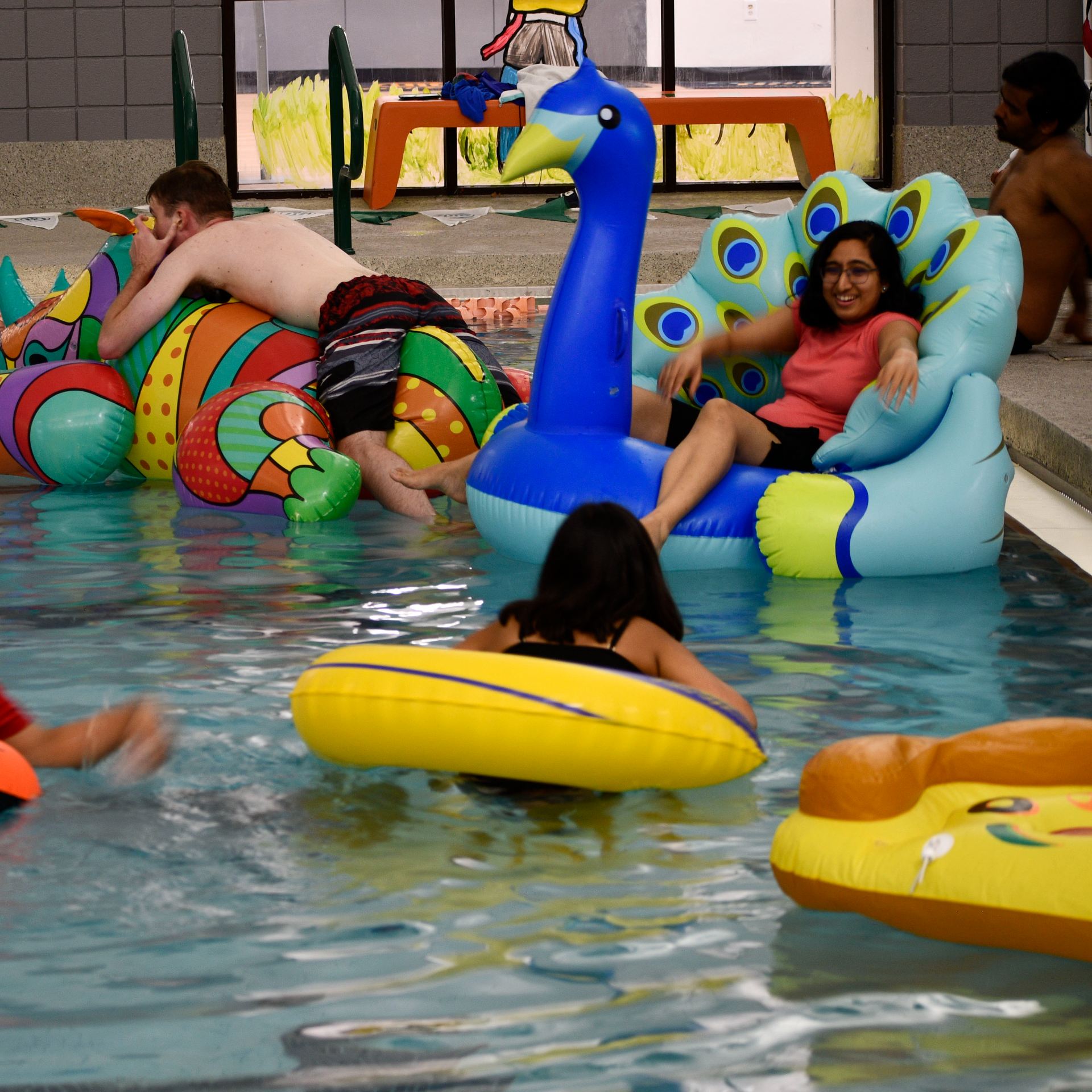 UT Dallas students lounge on pool inflatables in the activity center natatorium.  