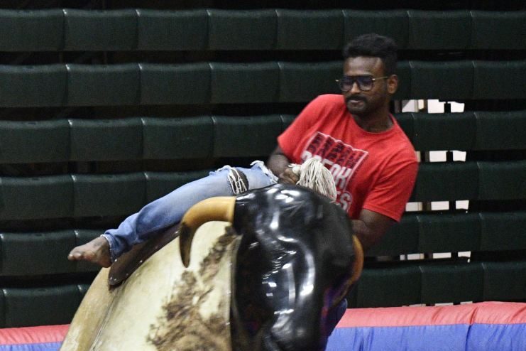 A person leans to remain in the saddle of a mechanical bull.  